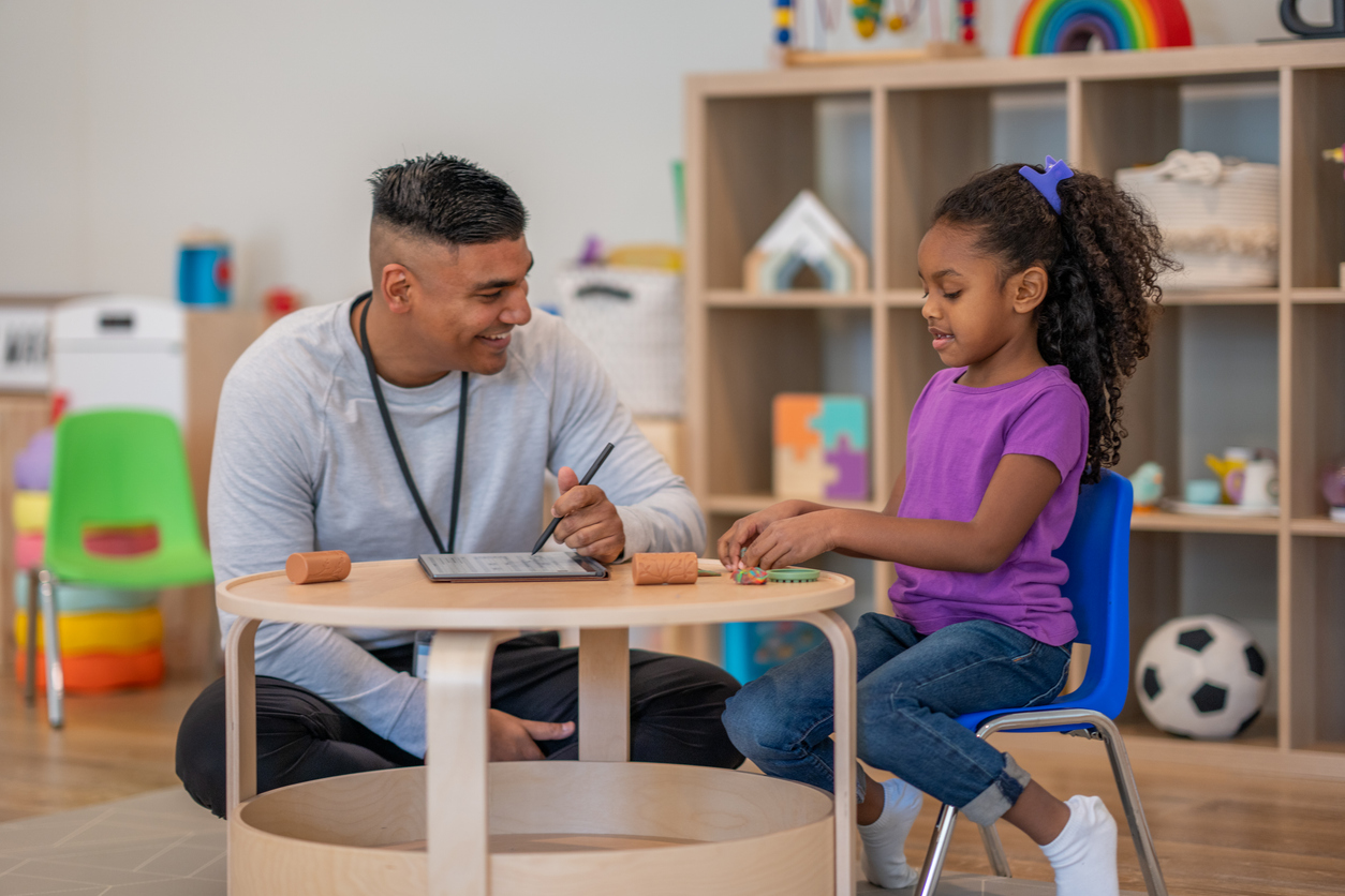 A special education teacher working one-on-one with a student at a classroom table.